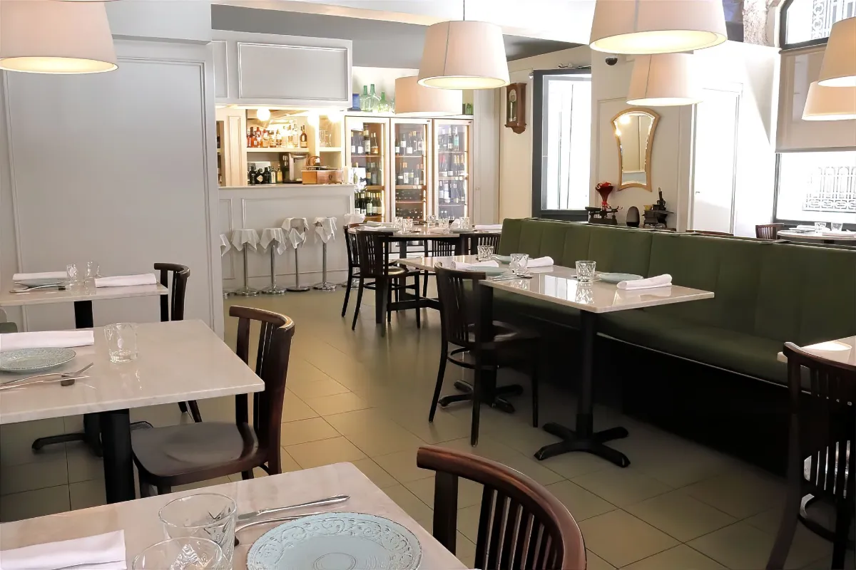 Sala del restaurant La Estrella 1924 amb banqueta verda, taules de marbre i la barra al fons